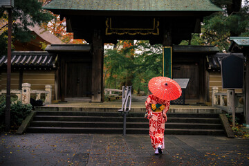 young girls tourist wearing red kimono and umbrella took a walk in park entrance