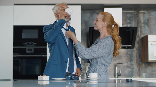 Senior woman help husband with tie indoors at home kitchen
