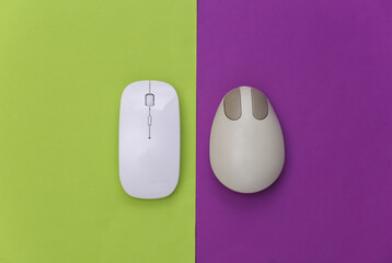 Old and modern pc mouse on purple green background. Top view