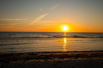 Obraz premium Beautiful golden sunset at the beach. Sun setting into the sea on tranquil evening. Nobody