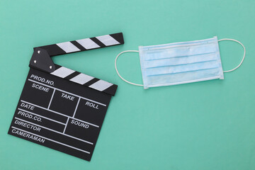 The downturn in the entertainment industry during covid-19. Movie clapper board with medical mask...