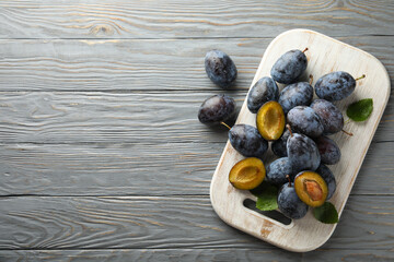 White board with fresh plums on wooden background