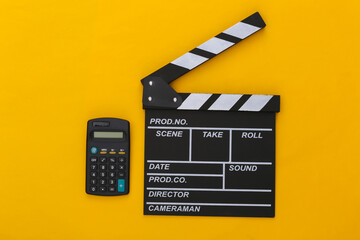 Movie clapper board and calculator on yellow background. Cinema fees. Filmmaking, Movie production....