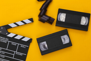 Retro Movie clapper board,  video cassette and film tape on yellow background. Filmmaking, Movie...