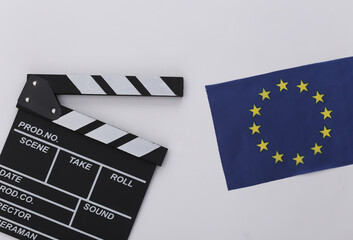 Naklejka premium Movie clapper board and EU flag on white background. Filmmaking, Movie production, Entertainment industry. Top view