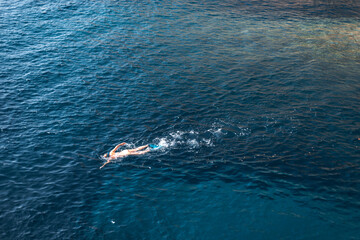 A woman enjoys a swim in crystal clear waters while wearing fins