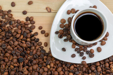 Espresso black coffee in a white cup with roasted coffee beans on wooden surface