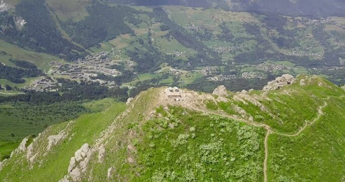Breathtaking drone video over the famous mountain peak Creve-Tete and its cross showing the village of Valmorel France 