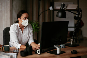 Fototapeta na wymiar Beautiful businesswoman with medical mask working in office. Covid-19 concept.
