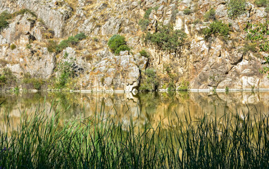View of the steep banks of Tagus river, reflected in the calm waters on a sunny day