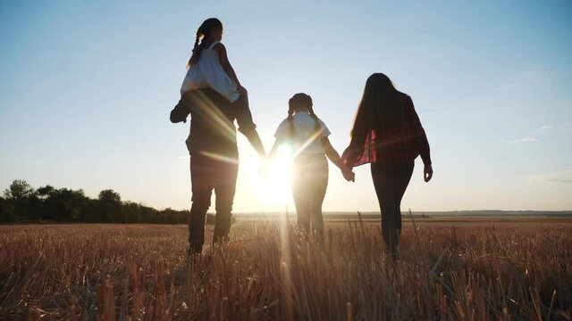 people in the park. happy family silhouette walk at sunset. mom dad and daughters walk holding hands in the park. happy family kid dream concept. parents fun and children walking back silhouette