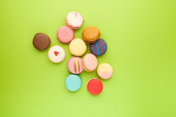 Fototapeta na wymiar An assortment of colorful macarons or macaroons lie randomly on a light green background. Top view, copy space