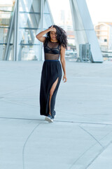 joven mujer de cabello negro rizado posando en la ciudad 