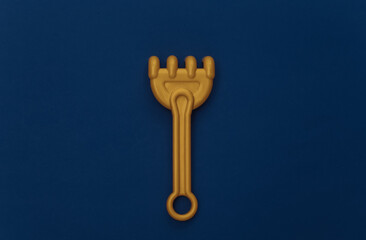 Toy sandbox rake on a classic blue background. Color 2020