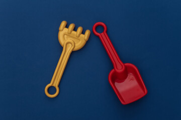Toy rake and shovel on a classic blue background. Color 2020
