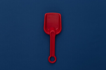 Toy red shovel on a classic blue background. Color 2020
