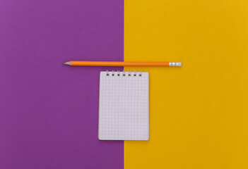 Notebook with pencil on purple yellow background. Top view