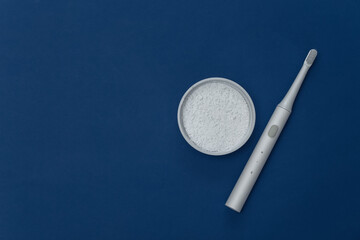 Electro toothbrush with tooth powder on classic blue background. Color 2020. Top view