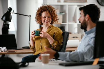 Colleagues in office. Businesswoman and businessman discussing work while drinking coffee..