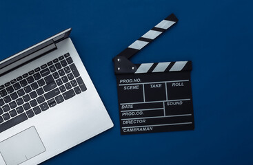 Fototapeta na wymiar Movie clapper board with laptop on classic blue background. Filmmaking, Movie production, Online cinema. Top view