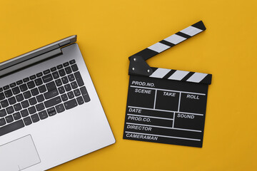 Fototapeta na wymiar Movie clapper board with laptop on yellow background. Filmmaking, Movie production, Online cinema. Top view