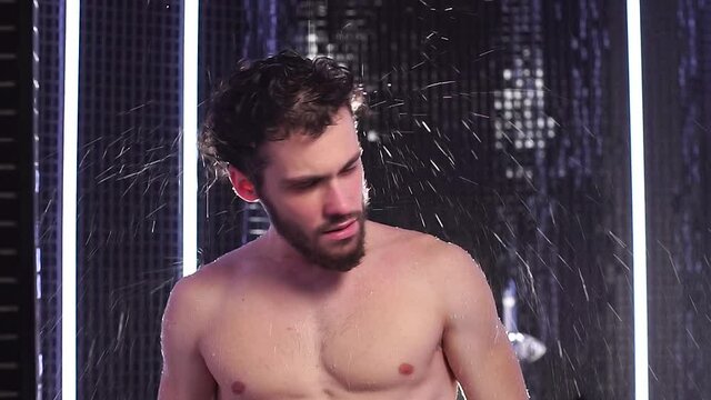 Take care of your skin and body. Attractive naked men take shower in Spa center. Slow motion