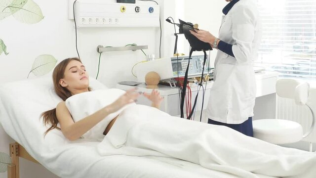 Beauty salon. Young attractive girl in a cosmetic salon lying on the table takes electro therapy.