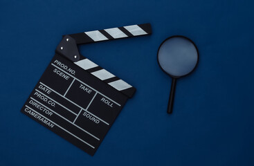 Movie clapper board with magnifier on classic blue background. Filmmaking, Movie production,...