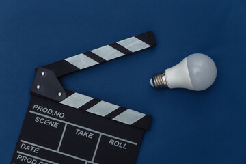 Movie clapper board with light bulb on classic blue background. Filmmaking, Movie production,...