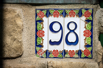 Close-up of house number 98 (ninety eight) on the wall in a small village. Liguria, Italy, Europe 