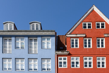Colorful houses in red and blue of the Nyhaven in Copenhagen Denmark photographed frontally on a sunny day with a bright blue sky.