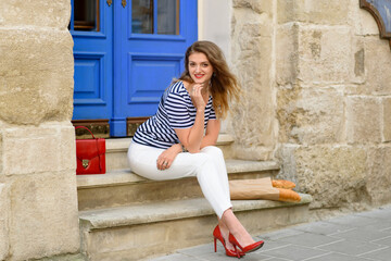 Young beautiful woman sits on the steps at the entrance to the restaurant.
