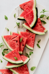 Watermelon slices with mint leaves on a white marble platter, shot from above
