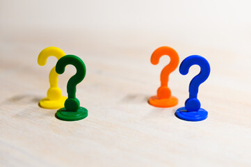 Problem solving and leadership illustrated with play figures in question mark shape in bright colors against white background.