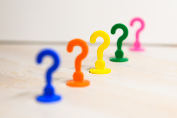 Problem solving and leadership illustrated with play figures in question mark shape in bright colors against white background.