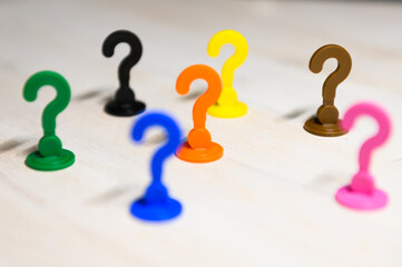 Problem solving and leadership illustrated with play figures in question mark shape in bright colors against white background.