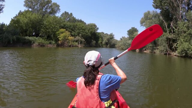 Young hispanic woman kayaking on the river Ter on a summer sunny day. Catalonia of Spain