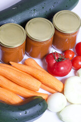 Vegetables for cooking squash caviar. Zucchini, carrots, onions and tomatoes on the table surface. Nearby are jars of squash caviar.