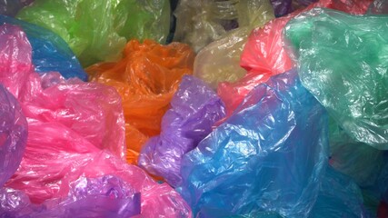 A lot of Colorful Single-use Plastic Shopping Bags throw away form a big pile. Plastic Packaging Pollution. Plastic trash in landfills and the ocean