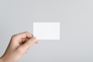 Obraz premium Business Card Mock-Up (85x55mm) - Male hands holding a blank card on a gray background.