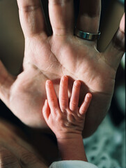 Newborn hand together with his father's hand

