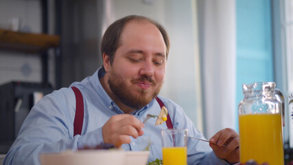 Portrait of overweight man having healthy breakfast in modern kitchen