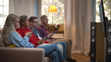 Diverse friends surfing internet on smartphone sitting on couch and watching surprising video on tv