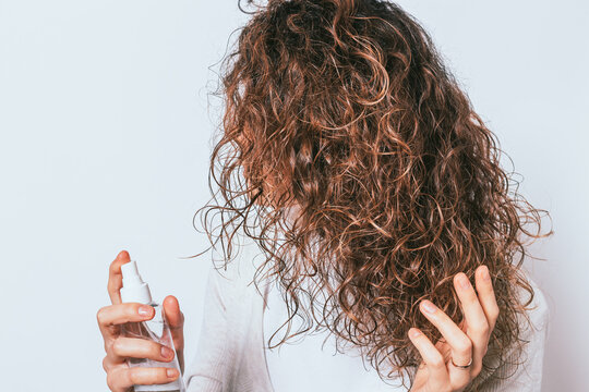 Woman applying moisturizing spray to her curly hair
