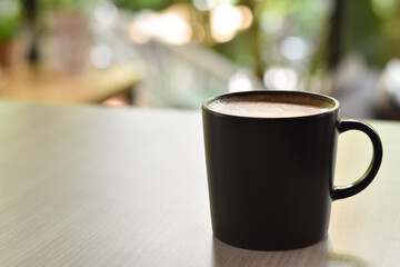 Hot coffee in black mug on wooden table.