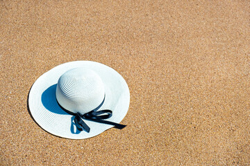 Fototapeta na wymiar White woman straw hat laying on tropical sand beach on sunny summer day. Vacations and destination travel concept.