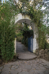 Fototapeta na wymiar white house entrance with small blue door and stone floor, surrounded by plants, photo with natural light