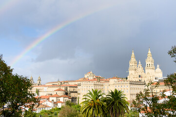 The famous cathedral of Santiago de Compostela and the old town with a big rainbow and a dark rain...