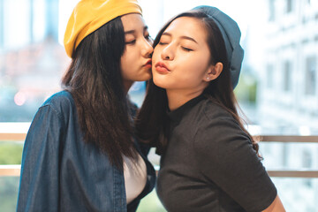 LGBT, portrait of lesbian couple Asian women using lips kissing under rainbow cloth,lesbian concepts.Two pretty women of different race play wrapping in a rainbow flag