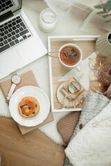 Breakfast. Laptop, mug of hot tea, bun, candle, eucalyptus in a vase. Cozy autumn. Home.